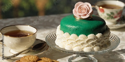 Classic Swedish Princess cake, bright green marzipan dome, pink sugar rose on top, elegant tea time setting.
