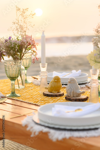 Romantic beach dinner setting with ceramic birds and sunset