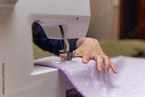 Принти на полотні Close up of a woman's hands sewing light purple star-patterned fabric using a mo