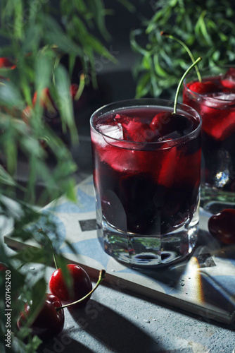 Glasses with cold cherry drink with ice in low key	