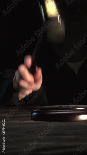 Judge's hand striking gavel on black background close-up, final decision, announcement of the verdict, vertical video