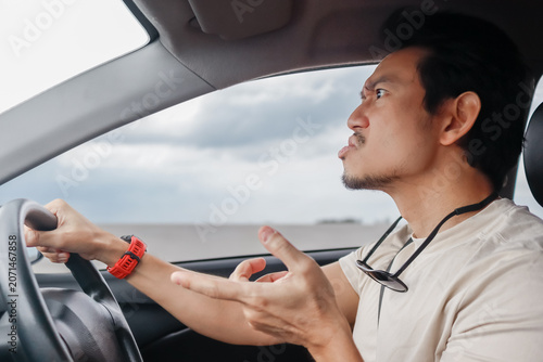 Fotografie Frustrated Asian Thai man driving his car, expressing annoyance and anger on the road