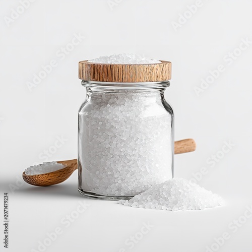 Glass jar with salt, wooden spoon on white background