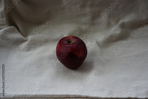 Tableau sur toile Close-up of one perfect dark red apple against the background of natural linen fabric
