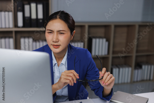 Fotografie Asian businesswoman concentrating on computer screen at dark office