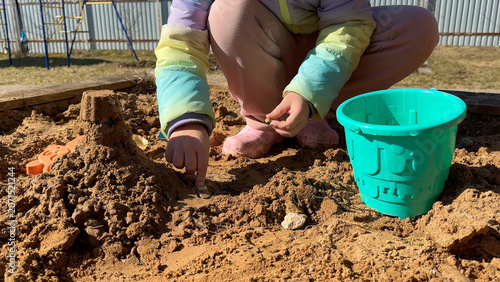 Konstfotografi The young explorer sifts sand through her colorful strainer, watching with fascination as the fine particles fall through the holes