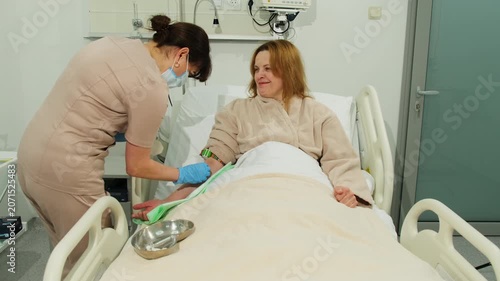 Nurse places iv catheter into woman arm during bedside procedure. Medical worker guides needle carefully securing access point for treatment