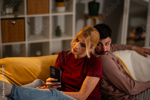 Fotografie Man spying on woman's smartphone, showing jealousy and mistrust