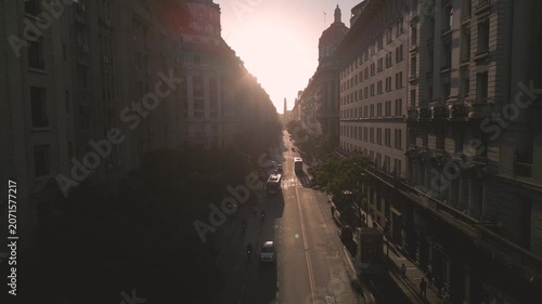 Sunset view over city street with buildings and cars in motion