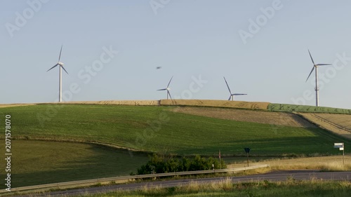 Wind turbines on farmland during sunny day with blue sky