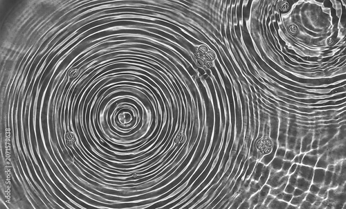 Abstract black and white water ripples creating concentric circles in a calm liquid surface