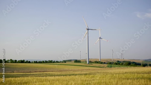 Wind turbines on farmland during sunny day with blue sky