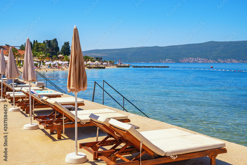 Fototapeta premium Beach vacations, chaise lounges and beach umbrellas. Montenegro, Bay of Kotor, Tivat