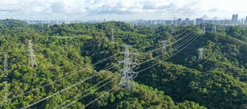 Panel kuchenny z motywem Aerial view of high voltage electricity tower on green mountain with modern city in the distance