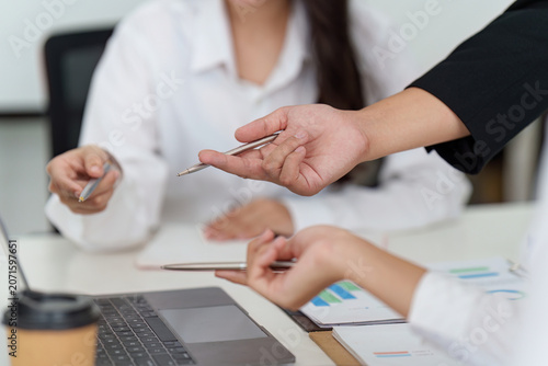 Cropped hands of businesspeople pointing at charts on desk for project collaboration