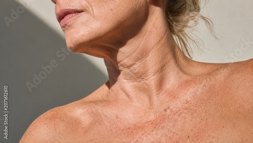 Close-up of mature woman neck and shoulder skin texture with natural wrinkles and light shadows