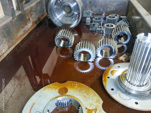Quadro su tela ​Heavy duty industrial steel spur gears and transmission components submerged in a lubricating fluid tray for cleaning or assembly