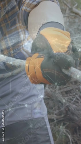 Vertical video: Gloved hands holding looped rope, pulling and tightening strand to secure brush