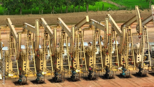 Принти на полотні Close aerial drone view of oil pump jacks operating in a structured field, highlighting global oil demand, supply stability, and continued reliance on fossil fuels amid energy transition efforts