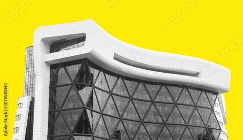 Curved modern building facade against bright yellow background. Contemporary architecture with glass atrium and geometric structure. Real estate,