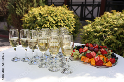 Glasses with sparkling drink and fresh fruit platter served on a festive table during a celebration.