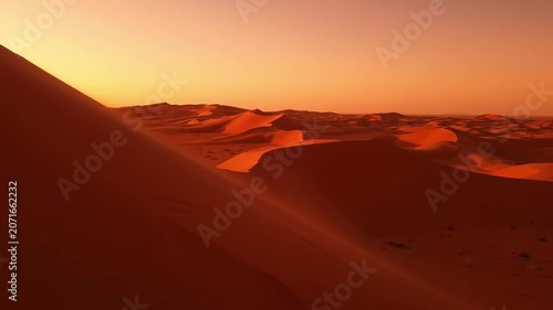 Golden hues dance across the rolling sand dunes as the sun sets on the horizon. The tranquil landscape exudes warmth and mystery, inviting exploration and contemplation.