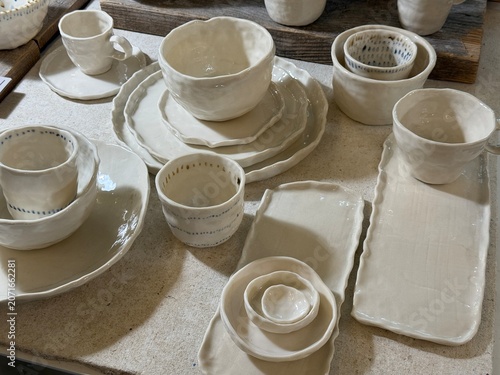 Billede på lærred Handmade ceramic dishes with cups, plates, and bowls displayed on a table at a c