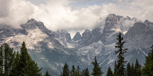 Bild auf Leinwand Dramatic Dolomite Peaks Rising Above Alpine Forest Under Storm Clouds