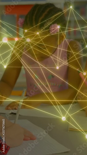 Vertical video: Students on teacher cue, writing at table in school, golden nodes moving over pages