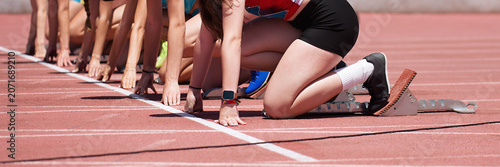 Group of female track athletes on starting blocks.Hands on the starting line. Athletes at the sprint start line in track and field