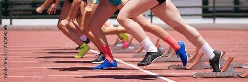 Group of female track athletes on starting blocks	started