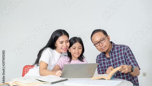 Asian Parents Helping Daughter with Online Homework on Laptop at Home