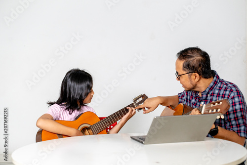 Asian Father Teaching His Young Daughter Fretboard Chords on Acoustic Guitar