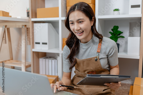 Young ecommerce entrepreneur preparing customer orders, labeling shipping boxes, managing inventory, tracking online sales and celebrating business growth while working from a modern home office.