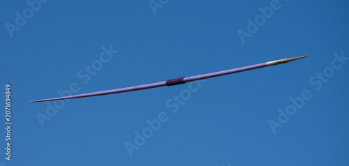 A javelin flying through the air in a stadium on a blue sky. Javelin throw