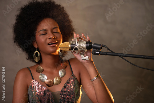 African female singer with an Afro hairstyle, wearing a beautiful, long, elegant dress, is enjoying the music she is singing.
