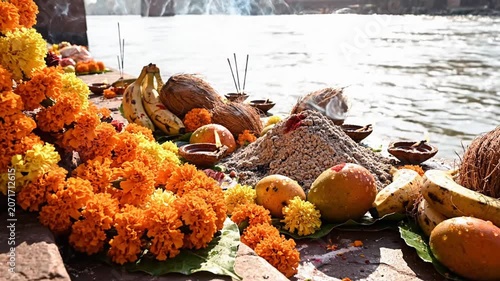 Close-up of marigold garlands and fruits for hindu ritual on the ganges river bank in bright daylight.