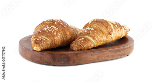 Golden brown croissants with crunchy topping served on a rustic wooden board