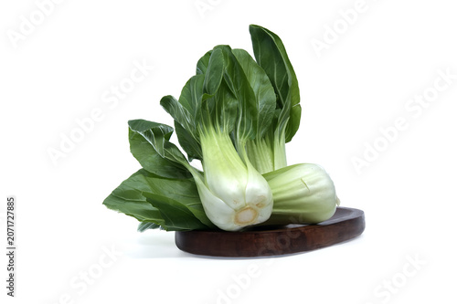 Fresh bok choy vegetables arranged on a wooden board against a clean white background