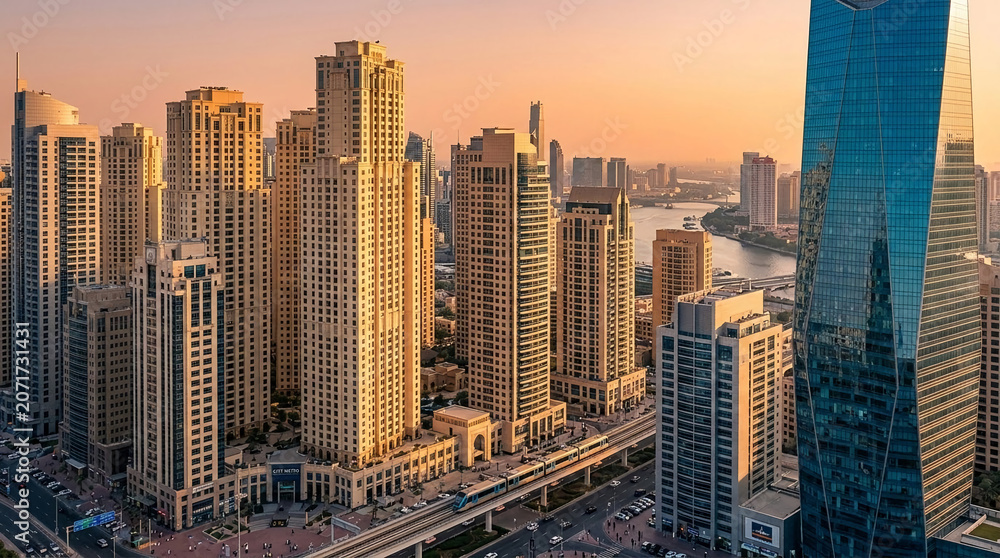 Obraz premium Aerial view of a modern cityscape with tall skyscrapers under a soft orange sunset, symbolizing urban development and metropolitan life