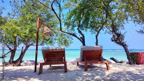 empty sun beds against serene ocean backdrop on tropical beach, turquoise sea water. Gili island Indonesia. Ideal for relaxation themes, vacation vibes and peaceful escape imagery