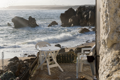 Chairs on a outdoor living area next to the ocean.