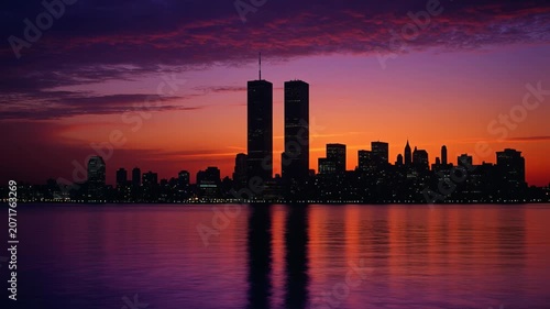Iconic twin towers silhouette against vibrant orange sunset over harbor water