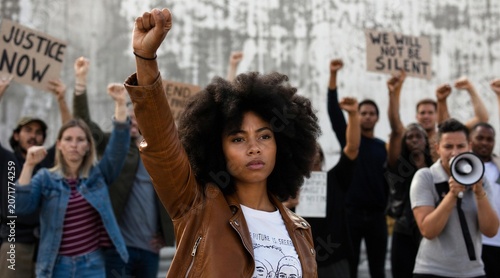 Naklejka Young Woman Raising Fist at Peaceful Protest for Justice and Equality