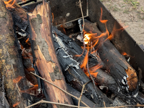 Fotografía Small flames flicker in the embers of a campfire