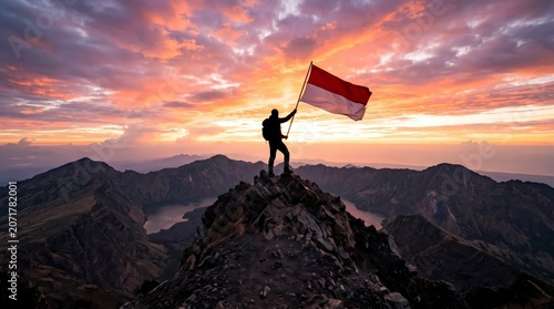 Person holding the Indonesian flag on a mountain peak at sunset