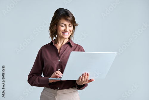 Canvas-taulu Latin mid-age ceo businesswoman holding laptop and looking at screen standing on background isolated