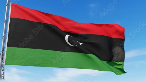 The national flag of Libya waves against a clear blue sky
