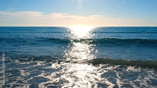 Beautiful sunset over the calm blue ocean waves on a sandy beach