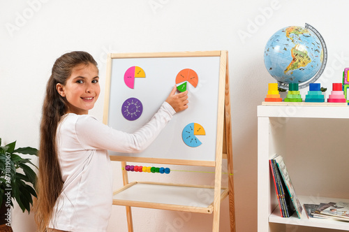 Obraz na plátne Child practicing basic math and fractions with magnetic circle segments on a whi